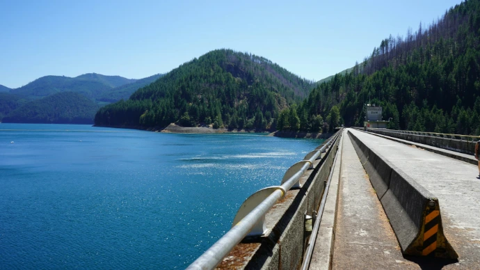 Dam and blue lake surrounded by forested mountains